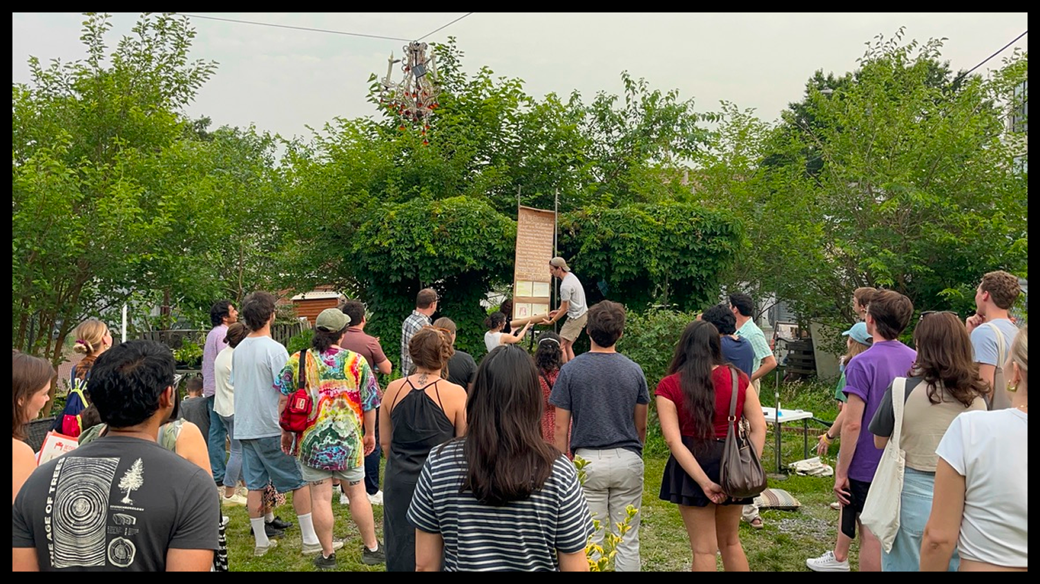 A crowd gathered outdoors around the unrolled dumb scroll